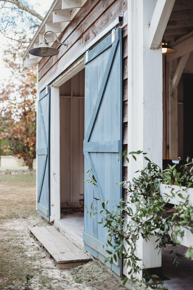 Rustic barn with open blue doors and draped greenery at Wavering Place, captured as venue detail during Morgan and Daniel’s wedding day in Eastover, SC