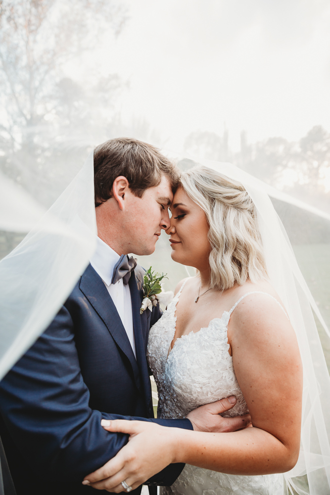 Intimate under-the-veil portrait of Morgan and Daniel touching foreheads with soft light and dreamy focus at Wavering Place