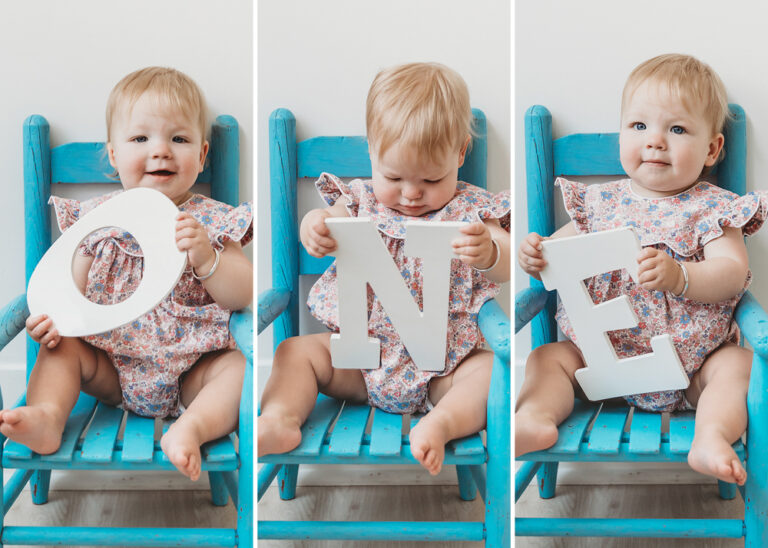 Hadley seated in a blue chair holding O-N-E letters, celebrating her first birthday at Reflection Images by Tracy Rowell in Florence SC