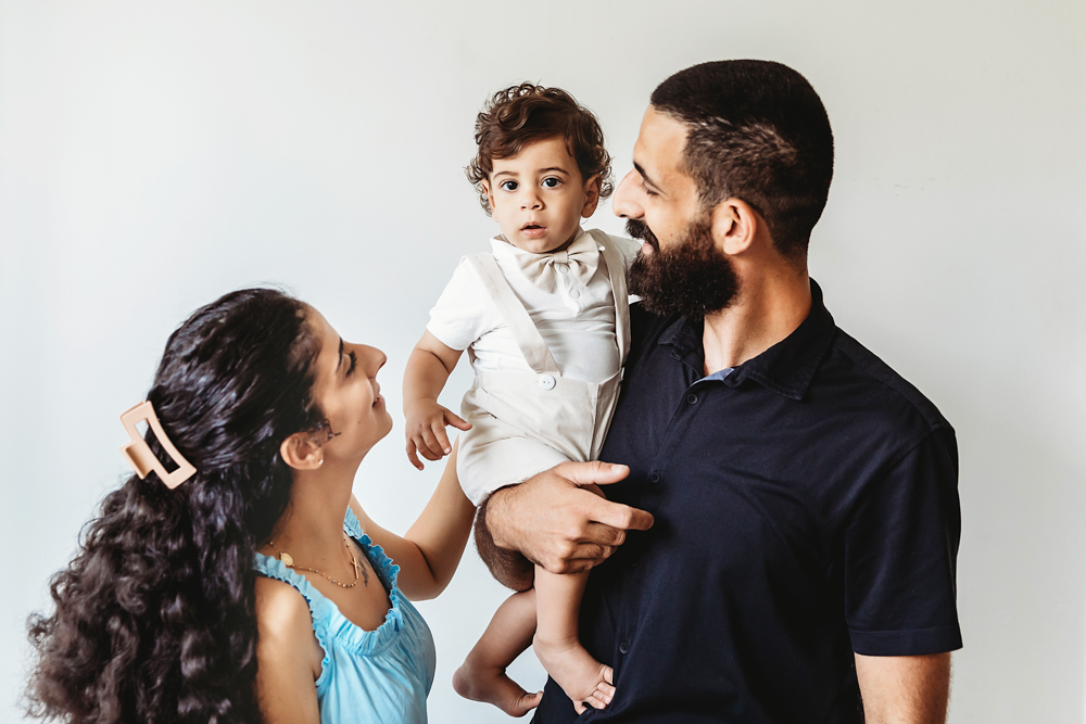 Lucas held by dad while mom smiles up at him during a bright studio family portrait at Reflection Images by Tracy Rowell in Florence SC