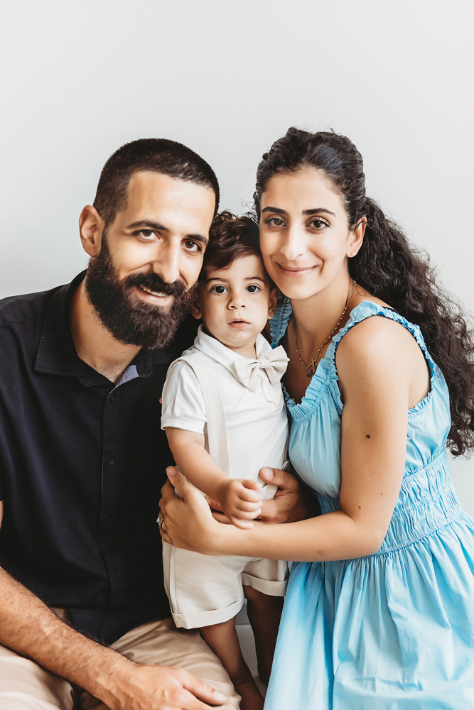 Mom and dad cuddling Lucas closely in a warm family portrait against a soft white studio wall at Reflection Images by Tracy Rowell in Florence SC