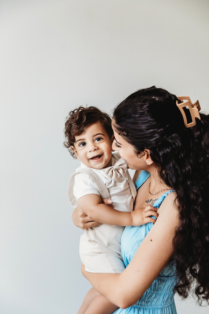 Mom holding Lucas in a side profile pose while he smiles toward the camera in bright studio light at Reflection Images by Tracy Rowell in Florence SC