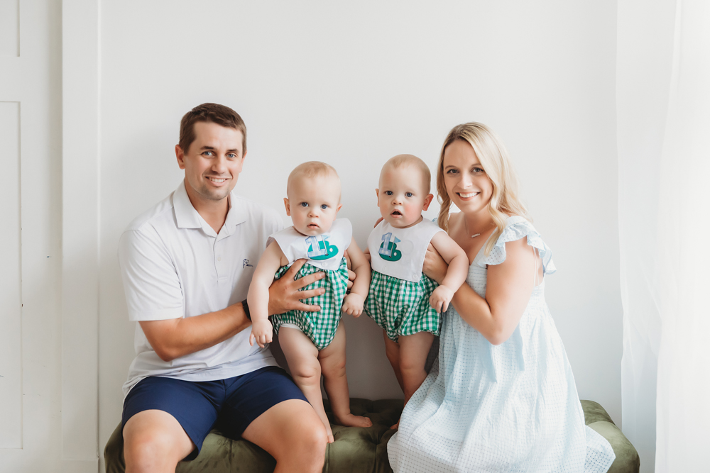Smiling family portrait with parents holding twins between them at Reflection Images by Tracy Rowell in Florence SC
