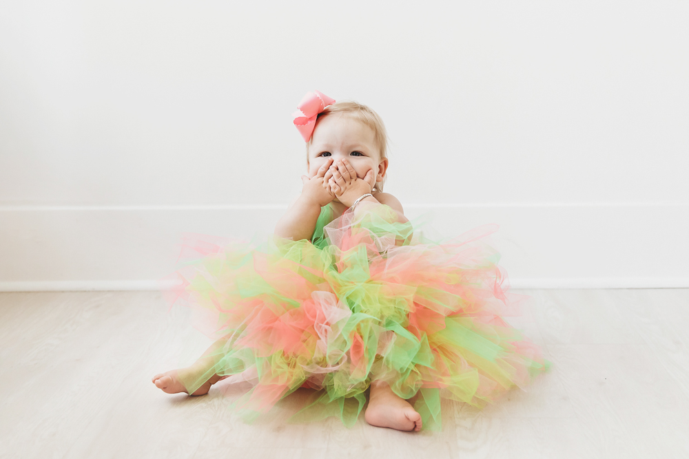 Hadley wearing a bright rainbow tulle tutu, blowing kisses with hands over her mouth at Reflection Images by Tracy Rowell in Florence SC