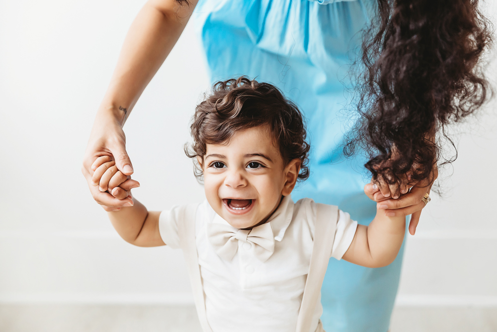 Lucas smiling widely while holding moms hands and practicing steps in soft natural studio light at Reflection Images by Tracy Rowell in Florence SC