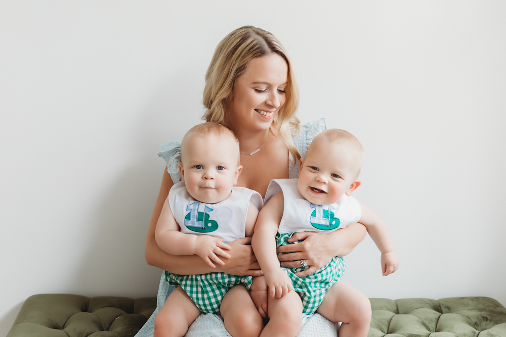 Mom holding twins in green gingham outfits while sitting on bench at Reflection Images by Tracy Rowell in Florence SC