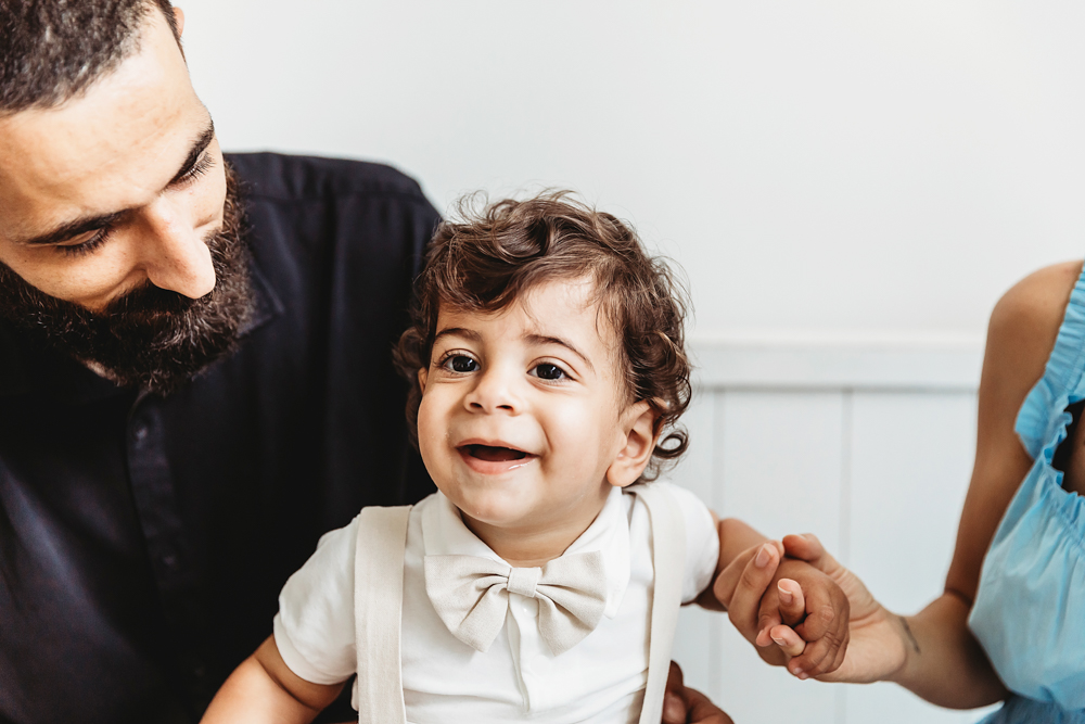 Lucas smiles while dad looks toward him and mom holds his hand during a bright bench portrait at Reflection Images by Tracy Rowell in Florence SC