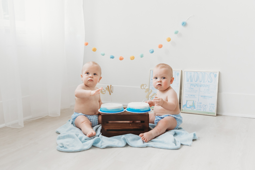 Twins in blue striped diaper covers with matching cakes and pastel garland during cake smash at Reflection Images by Tracy Rowell in Florence SC