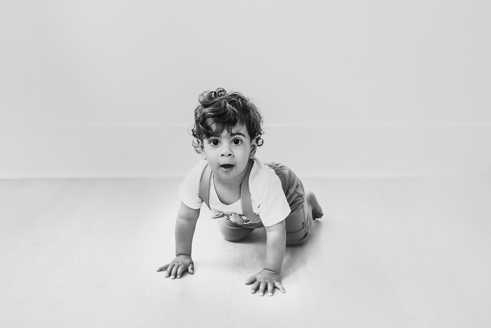 Black and white image of Lucas crawling toward the camera with wide eyes on a smooth studio floor at Reflection Images by Tracy Rowell in Florence SC