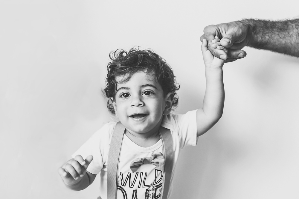 Black and white portrait of Lucas holding his dads hand while stepping forward with a joyful expression at Reflection Images by Tracy Rowell in Florence SC