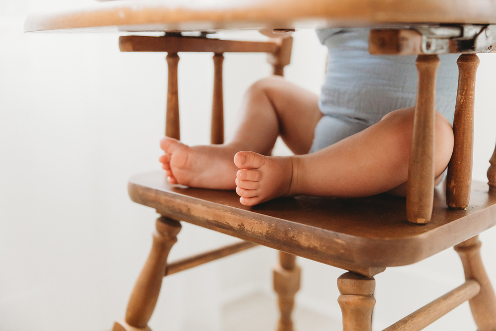 Baby's bare feet and legs on vintage wooden chair, soft natural lighting, florence sc photographer portrait session