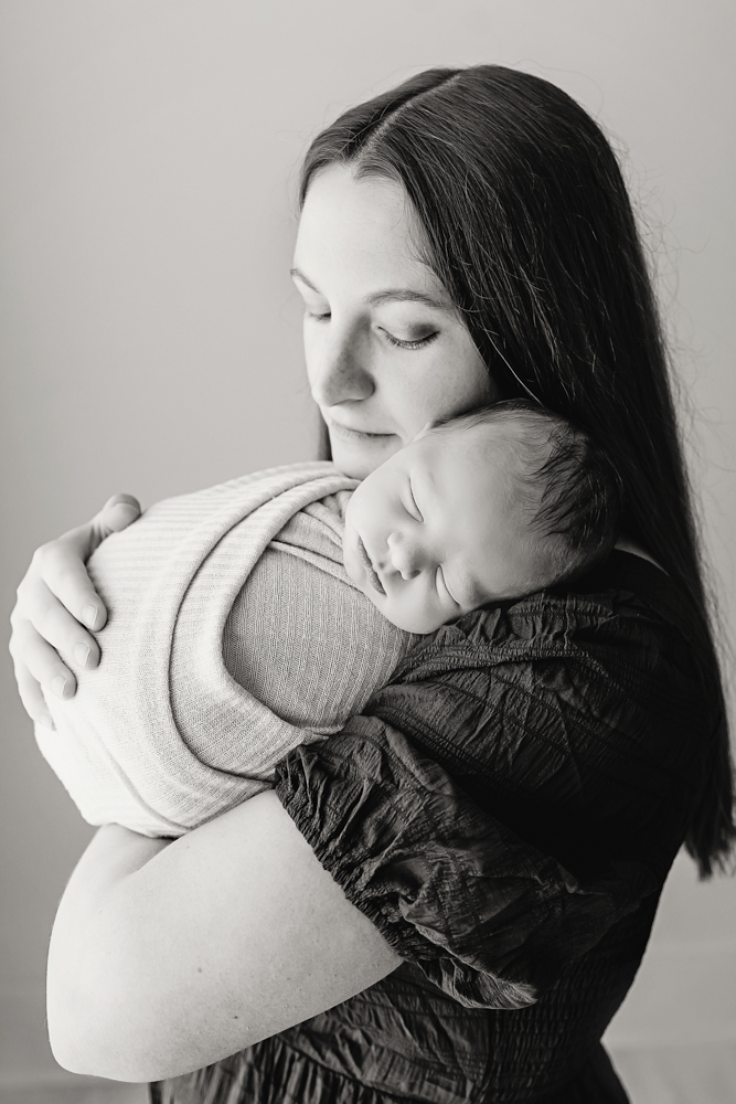 Mother cradling sleeping newborn in knit wrap, black and white portrait by florence sc newborn photographer