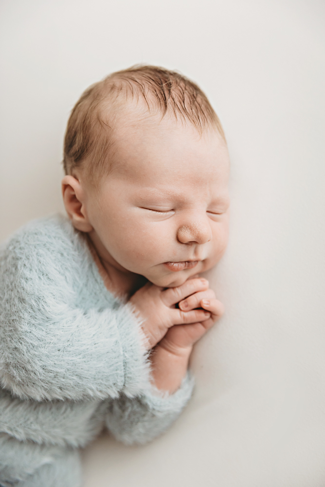 Peaceful newborn baby sleeping wrapped in soft mint green blanket on cream backdrop by florence sc photographer
