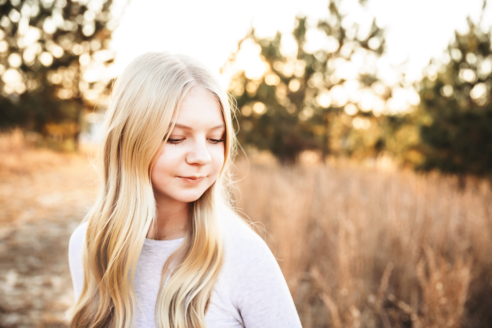 Teen girl with long blonde hair in white sweater, golden hour lighting, autumn field backdrop, professional photography near me