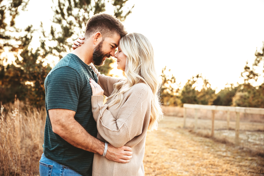 Adult couple embracing intimately in golden hour light, man in teal shirt, woman in beige sweater, professional photography studio