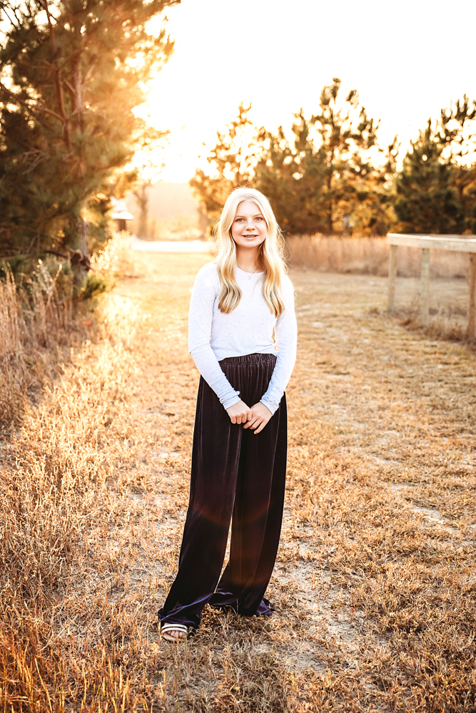 Teen in white top and black wide-leg pants smiling in golden sunset field, Reflection Images by Tracy Rowell