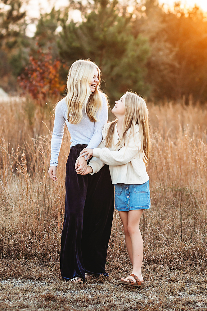 Professional fall family pictures of smiling mother and daughter in golden field, autumn light, casual outfits