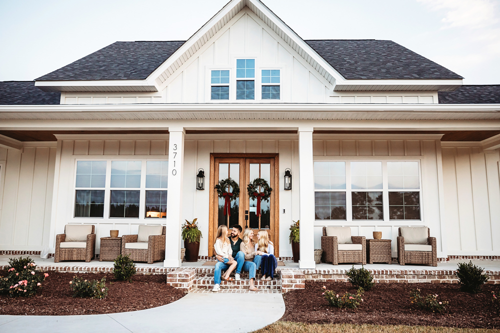Family of four sitting on brick front porch steps of modern farmhouse home, florence sc fall family photographer