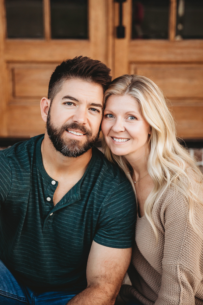 Smiling couple embracing indoors, man in green striped polo, blonde woman in beige sweater by florence sc photographer