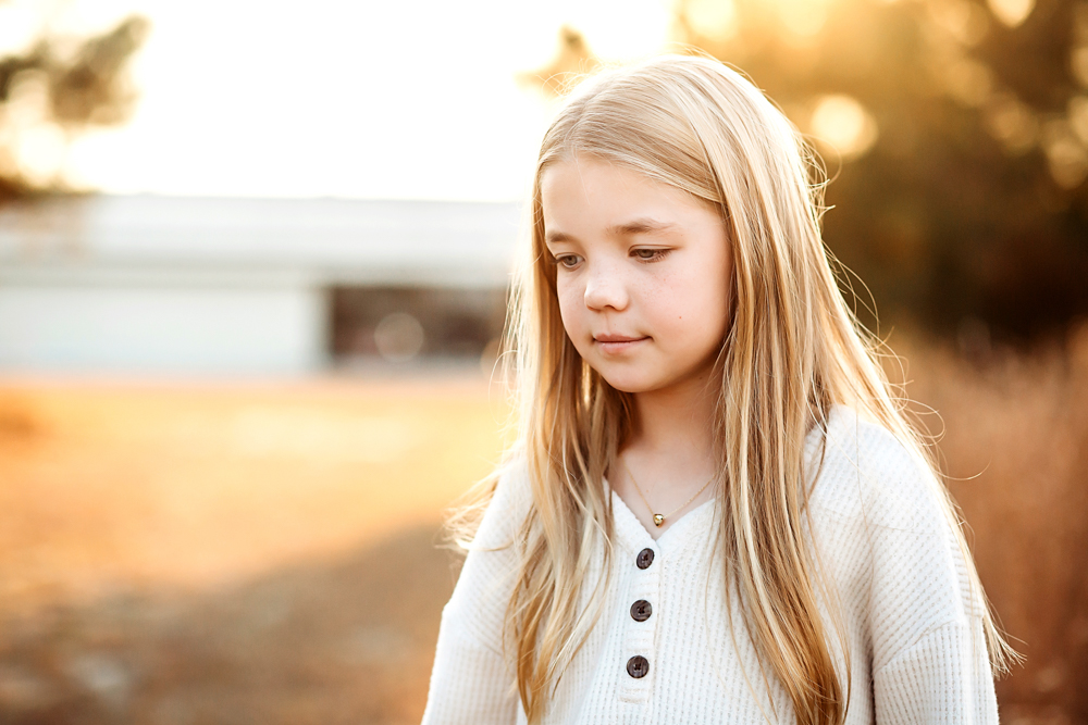 Young girl with long blonde hair in white button-up sweater, golden hour lighting, Reflection Images by Tracy Rowell