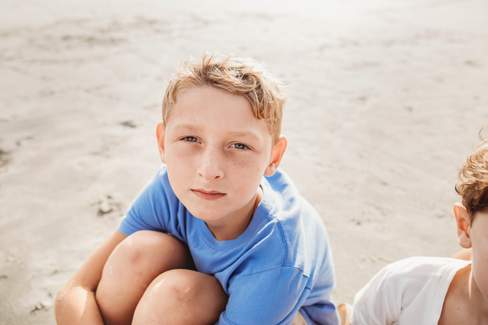 Boy with freckles in a cornflower blue crew neck shirt at Pawleys Island SC during a beach family session.