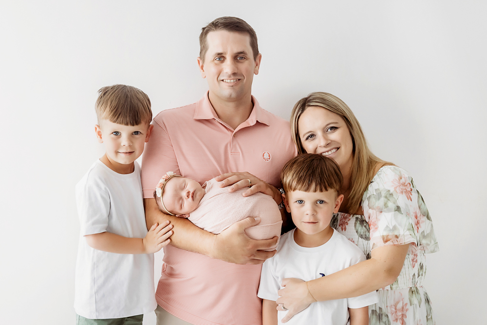 Family newborn session by Reflection Images in Florence SC featuring parents, two sons, and baby in a blush knit wrap.