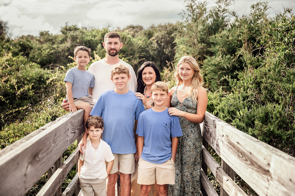 Culpepper family beach photography in Pawleys Island SC with sons in blue t-shirts and ivory linen shorts on boardwalk.