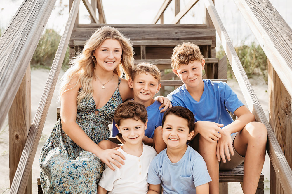 Smiling Culpepper siblings on Pawleys Island SC wooden dunes stairs for beach family photography in blue and ivory tones.