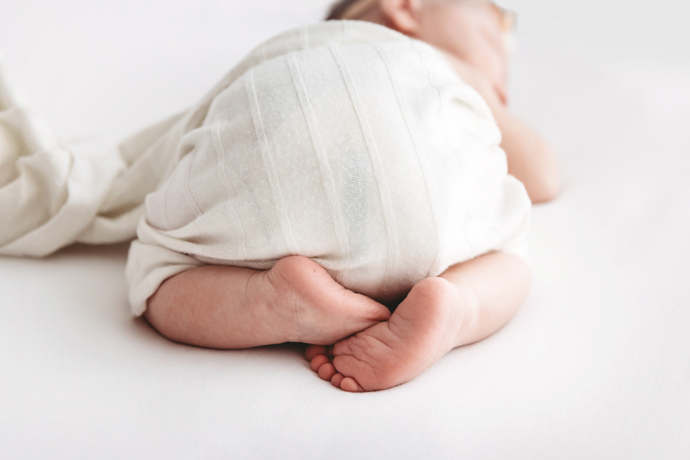 Sleeping newborn in ivory ribbed knit wrap on white backdrop by Florence SC newborn photographer Reflection Images.