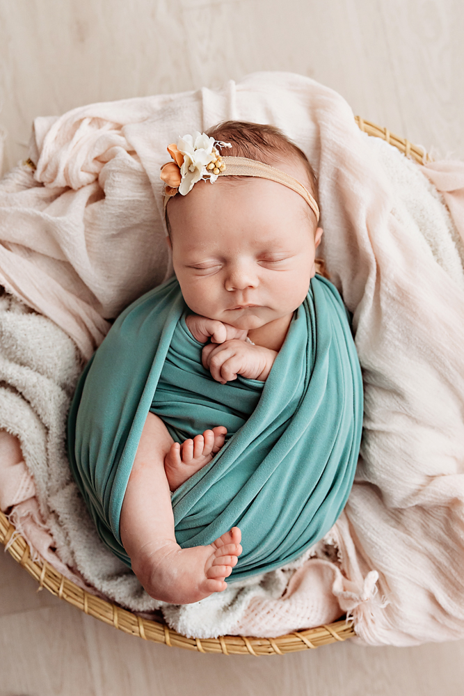 newborn sleeping in baby wrap laying in basket