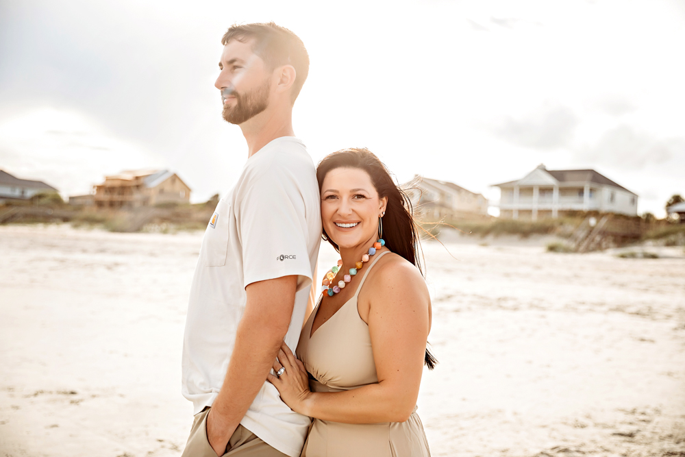 Couple standing back to back at Pawleys Island SC beach, tan dress and cream shirt by beach family photographer.