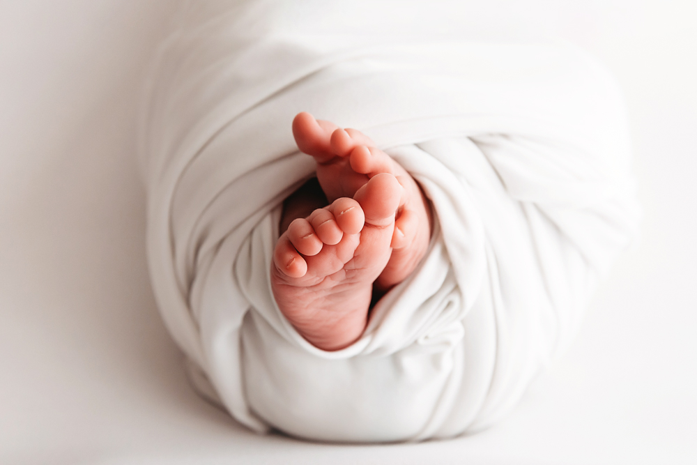 Tiny newborn feet peeking from a soft ivory knit wrap by Tracy Rowell, Florence SC newborn photographer.