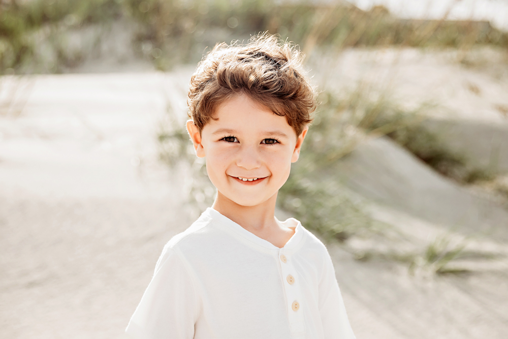 Smiling boy in ivory cotton henley shirt during beach family photography session in Pawleys Island SC.