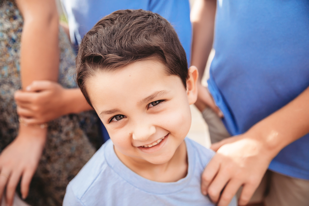 Young boy in a sky blue crew neck shirt smiles at camera during Pawleys Island SC family beach photography session.