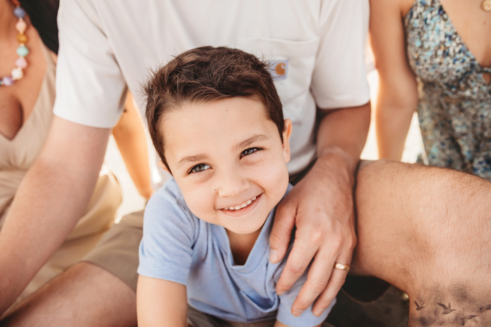 Smiling boy in periwinkle blue t-shirt with family at Pawleys Island SC by family photographer.