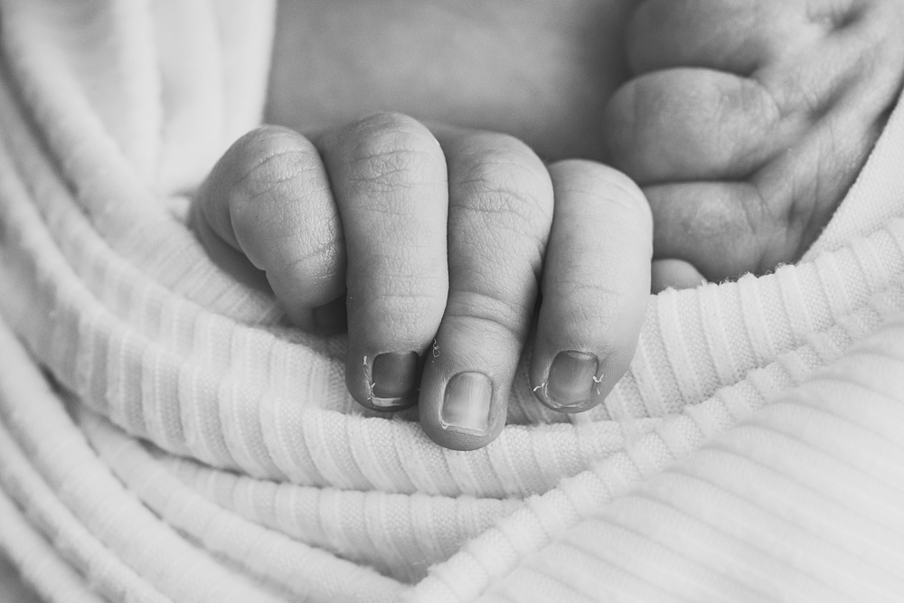 Black and white newborn macro of baby Gracyn's tiny hand resting in ivory knit wrap by Florence SC photographer Tracy Rowell.