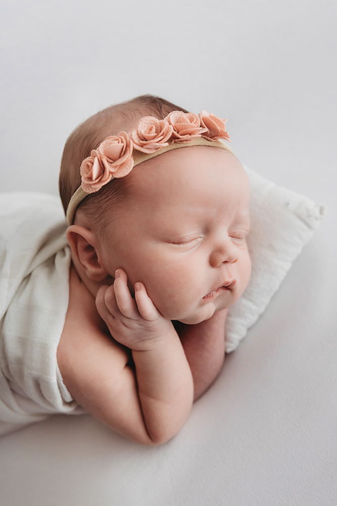 Newborn girl Gracyn, Florence SC, by Reflection Images. Sleeping baby wears peach floral headband and ivory muslin wrap.