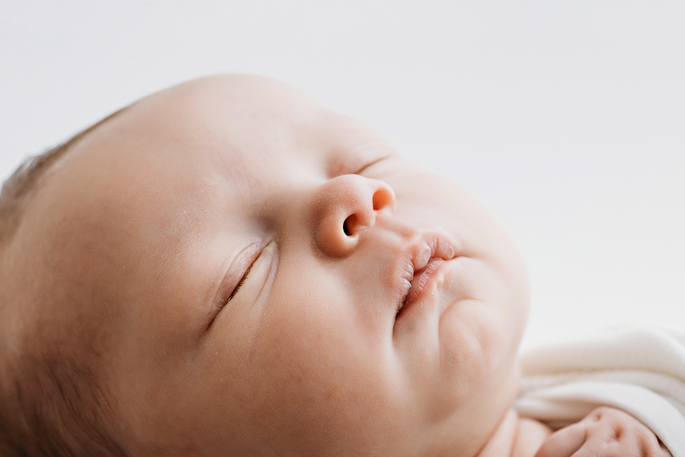 Sleeping baby in ivory swaddle, close-up newborn portrait by Tracy Rowell, Florence SC newborn photographer.