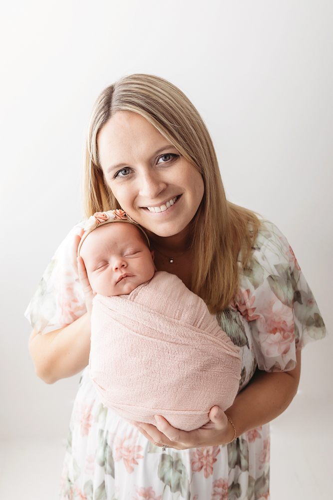 Mother holding newborn swaddled in dusty rose knit wrap with floral headband by Florence SC photographer Tracy Rowell.