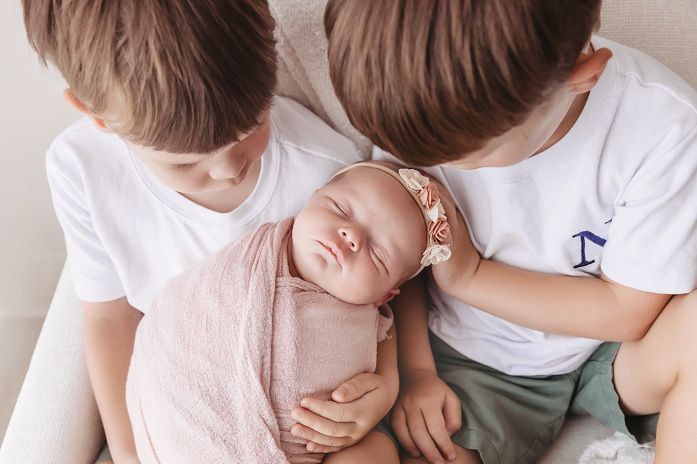 Newborn girl wrapped in dusty rose muslin held by twin brothers, by Florence SC photographer sibling poses Reflection Images.